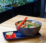 Laksa in a black bowl with accompanying lime and chillis 