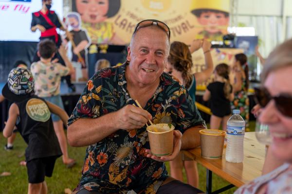 Person enjoying laksa in front of the marquee at the Darwin International Laksa Festival 2021